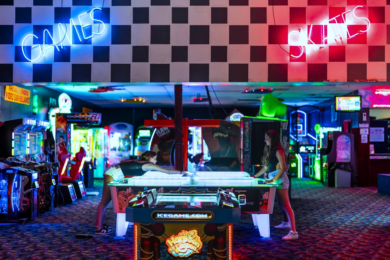 Arcade games and air hockey glowing under neon lighting
