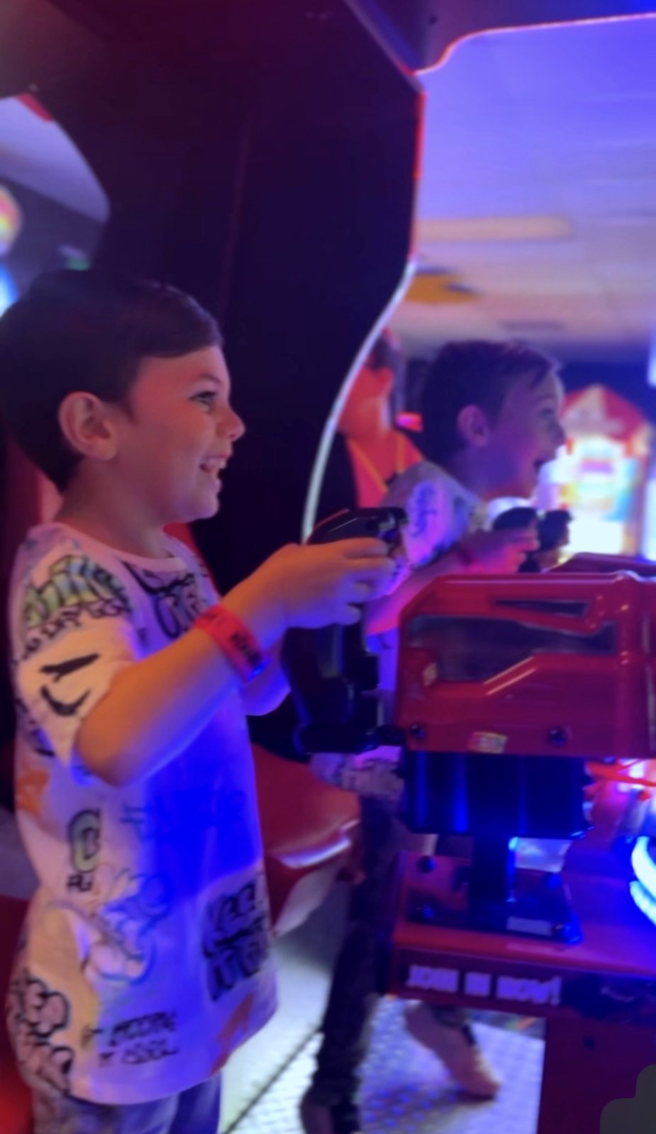A kid smiling while playing an arcade game