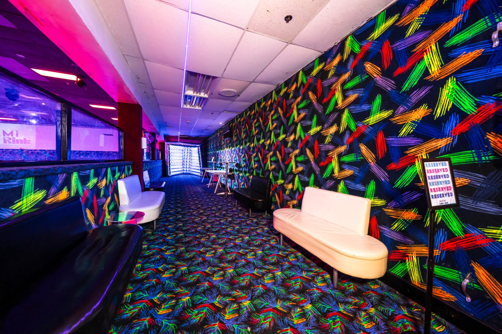 Corridor with a colorful neon arrow-pattern wall and seating