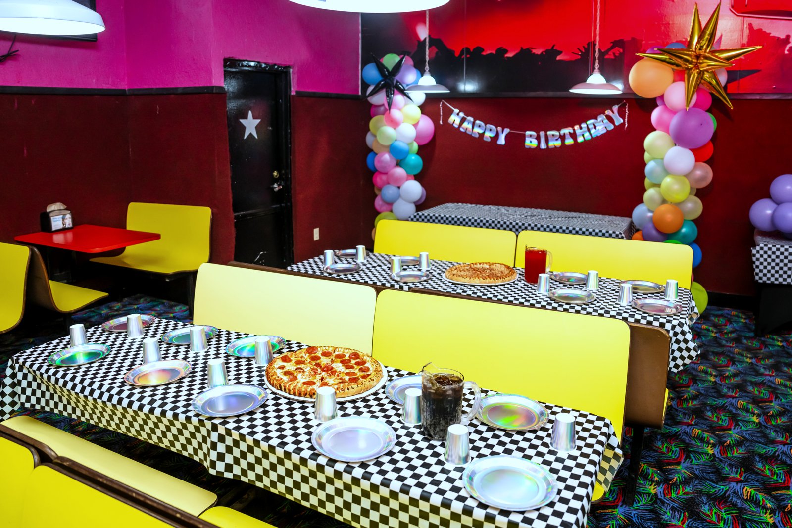 A set birthday party table with balloons and pizza in the yellow booths