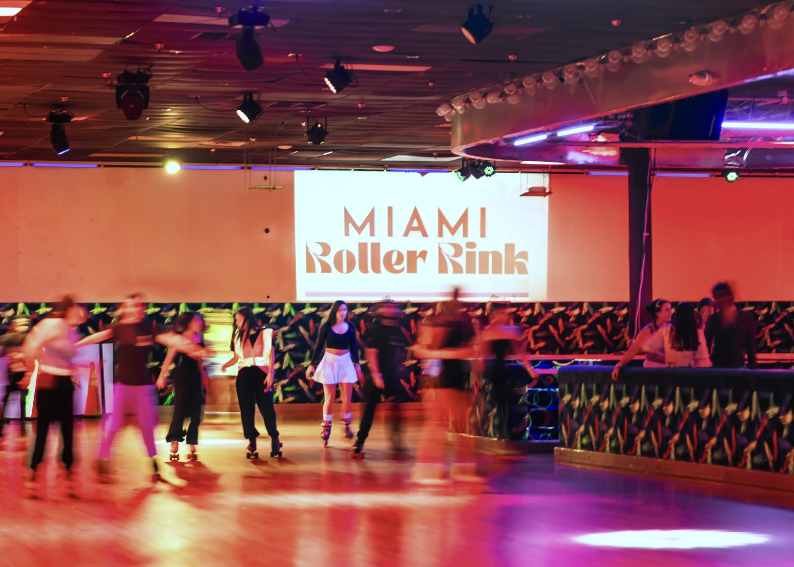 Skaters in motion on the floor in front of the Miami Roller Rink wall